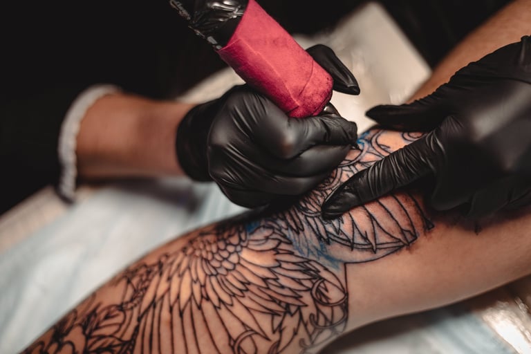 Professional tattoo artist makes a tattoo on a young man's leg