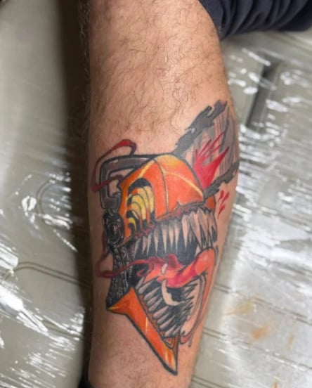 Colorful tattoo on forearm featuring an orange and red fish with black wings and flames