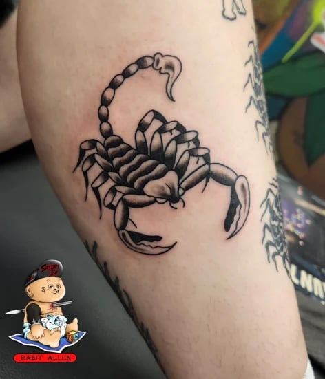 Black ink scorpion tattoo on upper arm with detailed segmented body and curved tail