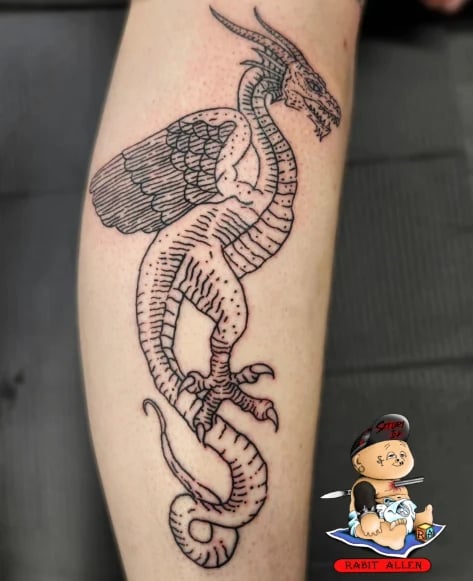 Black and white dragon tattoo on a leg, featuring detailed scales and wings in a vertical design with intricate line work